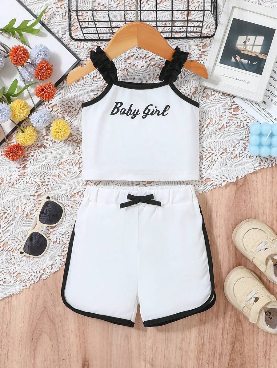 Baby Girl Casual Sports-Inspired Fashion Outfit, Black & White Color Block Design. Ruffled Shoulder Strap Top With "Baby Girl" Print, Paired With Loose White Shorts With Black Contrast Trim. Accented With Black Bowknot At Waist, Suitable For Everyday Wear, Family Gatherings And Relaxed Outdoor Activities.