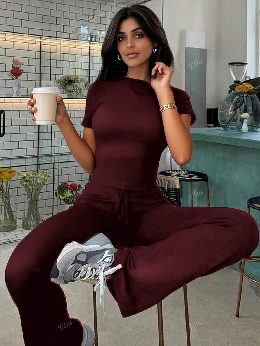 Tuta sportiva da donna alla moda per la primavera, con top a maniche corte che scopre la pancia e pantaloni a zampa aderenti con lacci