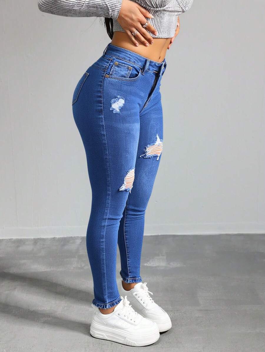 Jeans ajustados de cintura alta en azul con desgarros, tela suave y elástica, ideal para estilos casuales y versátiles