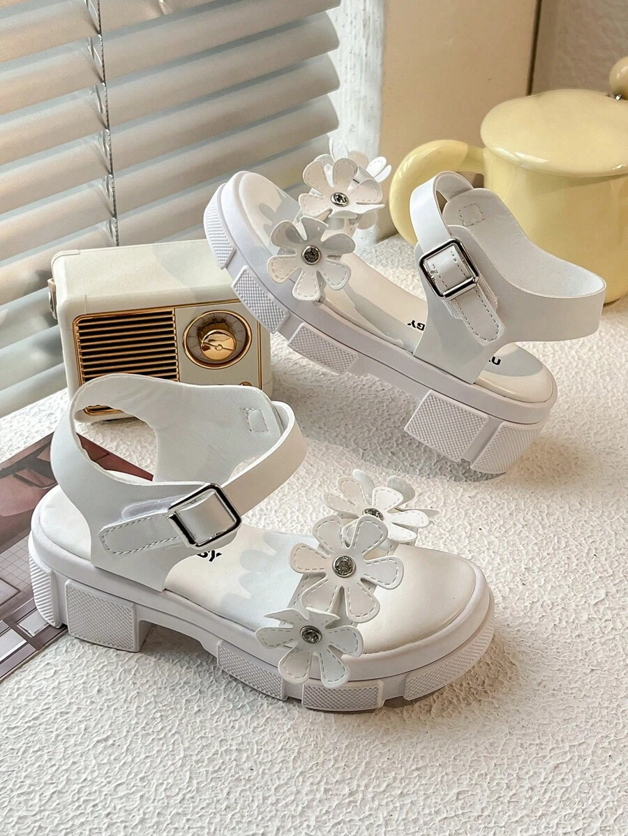 Un par de sandalias de plataforma blancas de moda de verano para niñas de 3 a 12 años, con elementos decorativos florales para un toque romántico. La parte superior es suave y cómoda, con diseño de gancho y lazo para un ajuste fácil, ya sea para juegos en interiores o paseos al aire libre, puede proporcionar un acompañamiento cómodo para los niños.