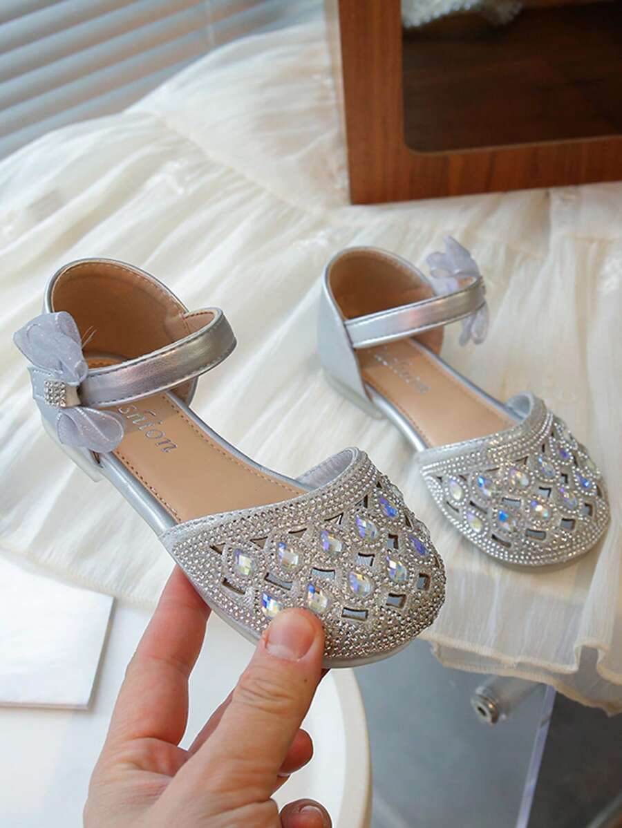 Un par de zapatos planos para niñas de estilo princesa dulce con decoraciones de lazo con diamantes de agua y hebillas para uso en fiestas y días festivos