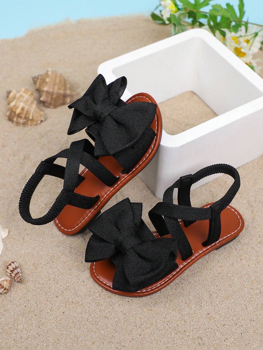 1 par de sandalias planas de unicolor para niñas, con diseño de tiras cruzadas con decoración de moño, y suela suave y cómoda, adecuada para salidas de verano, viajes a la playa y vacaciones de las niñas