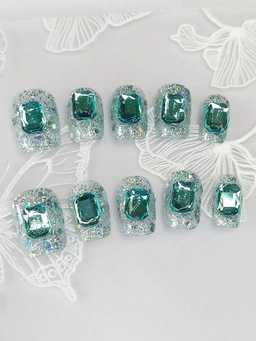 1 ensemble de 10 pièces d'ongles carrés courts et exquis avec de fins paillettes irisées peintes à la main et des pierres précieuses bleu saphir glacé. Cet accessoire d'ongles faux de style minimaliste allonge la longueur des doigts et ajoute une touche de mode à vos ongles.