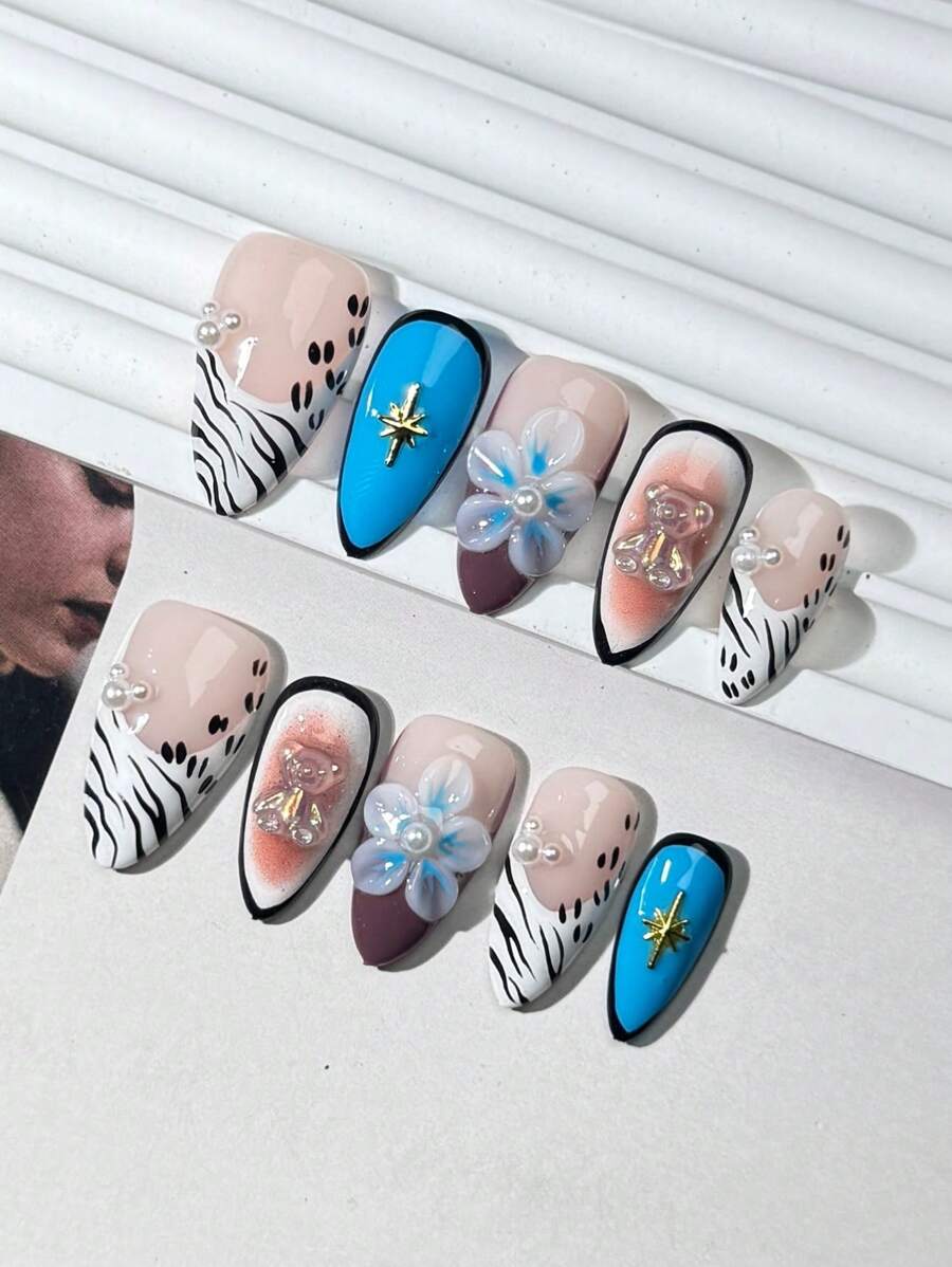 10 Stück handgefertigte Nagelsets, kurze Mandelform, beige mit blau und braun, schaffen eine elegante Atmosphäre. Sie sind dekoriert mit Perlen, Blumen, Bären, Metallsternen und anderen Verzierungen. Die Kombination von Eleganz und Niedlichkeit zeigt einen zarten und süßen europäischen und amerikanischen Stil, der sich für Damen und Mädchen zum Basteln von Nägeln für verschiedene Anlässe wie Zuhause, Arbeit und Partys eignet und wiederverwendet werden kann.