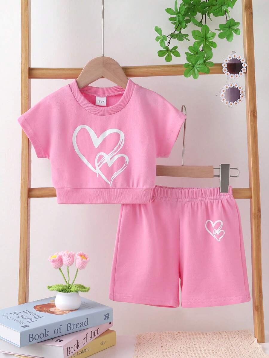 Set de 2 piezas de ropa informal y elegante para niñas, compuesto por sudadera de cuello redondo con gráfico de corazón y manga raglán de manga corta, y pantalones cortos, todo suave, transpirable y cómodo, adecuado para uso diario y vacaciones