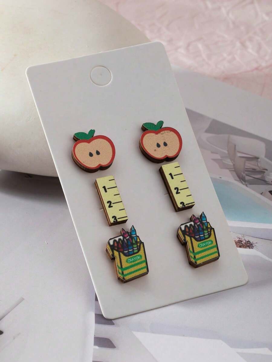 Um conjunto de 3 pares de brincos de madeira de desenho animado para o dia do professor, com tema de volta às aulas de réguas de maçã, giz de cera e brincos divertidos para presente de feriado