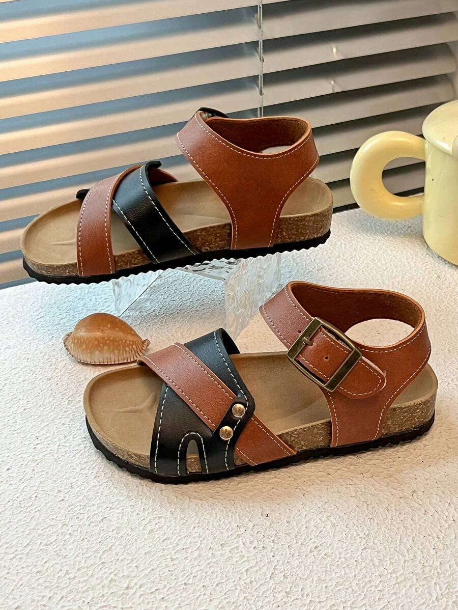 This Is A Pair Of Best-Selling Girls' Sandals. The Upper Is Made Of Brown And Black Leather. The Cross-Strap Design Adds A Sense Of Layering, And It Is Equipped With Metal Buckles To Adjust The Tightness. It Is Convenient To Put On And Take Off. The Upper Layer Of The Sole Is Made Of Cork, Which Fits The Feet Closely And Provides Comfort.