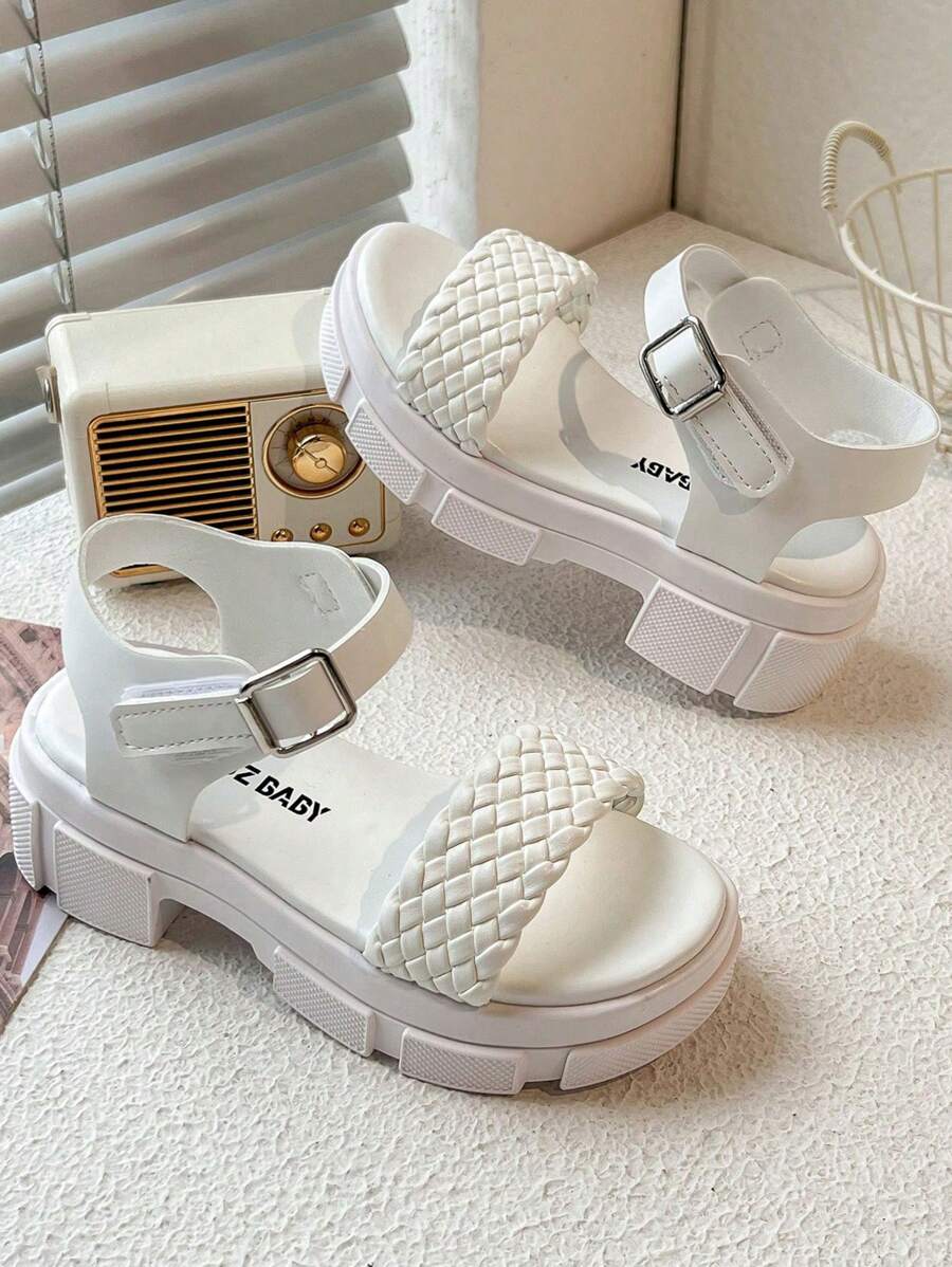 A Pair Of Children's/Girls' Sandals. The Main Body Of The Upper Is White. The Cross-Woven Straps Are In A Combination Of And Pink. There Is A Metal Buckle Strap At The Ankle.