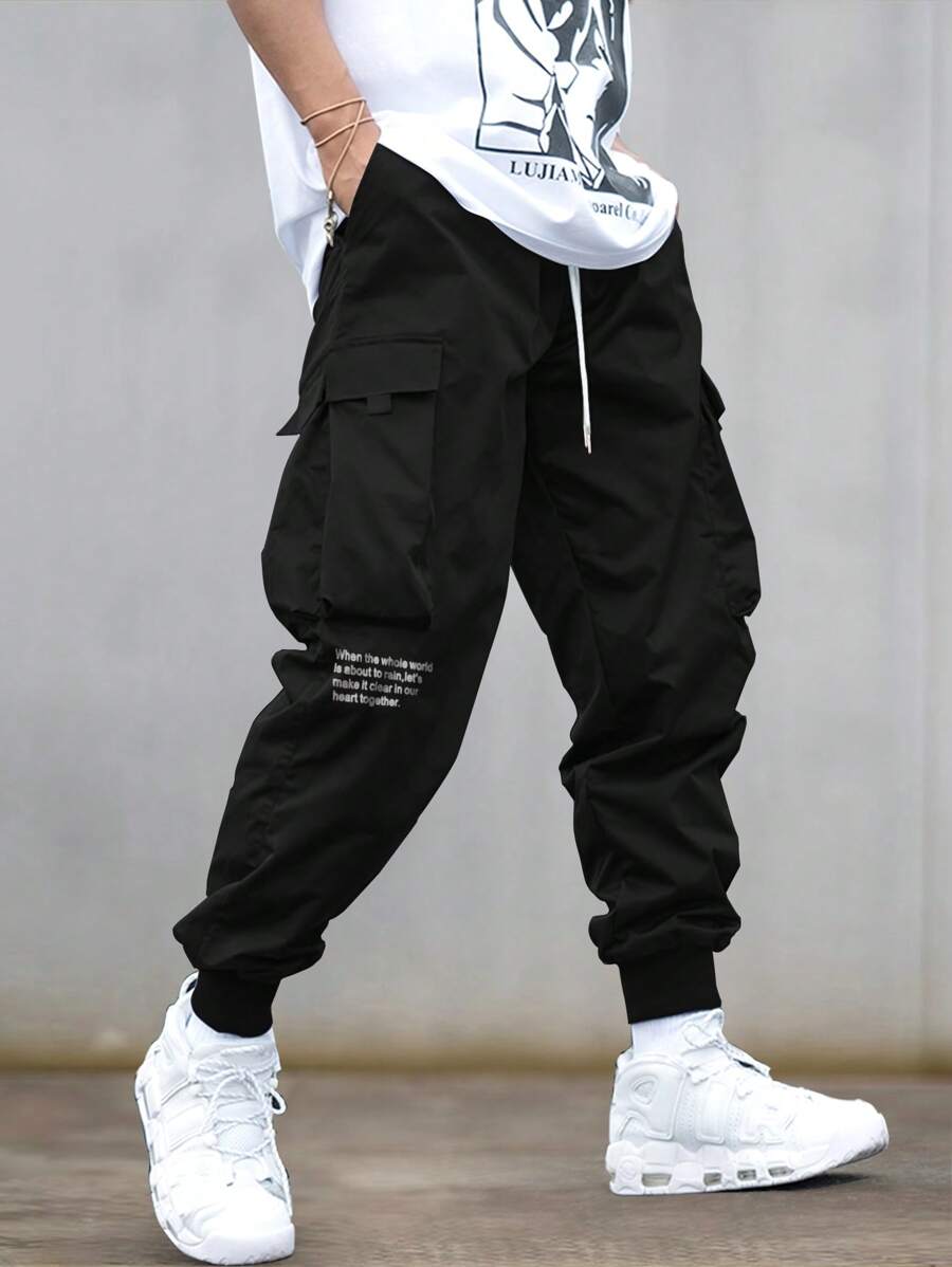 Manfinity EMRG Quần Cargo dáng rộng cho nam có họa tiết khẩu hiệu, túi có nắp và dây rút ở eo, quần dài màu đen, dành tặng chồng, quà tặng bạn trai - màu đen - Xem 1