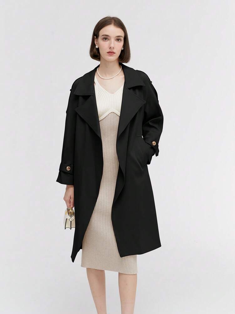 Woman in black trench coat with cream knit midi dress