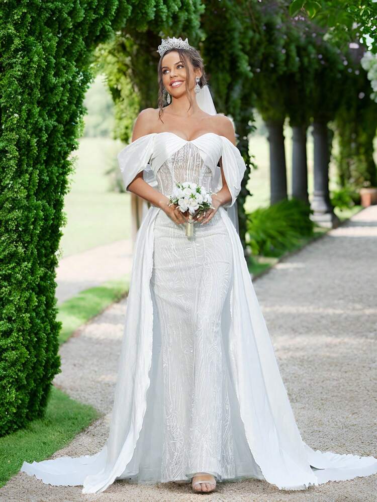 Elegant And Romantic Off-Shoulder Wedding Dress With Pleating Details And Embroidered Fabric.  Designed With Flounce And Layering