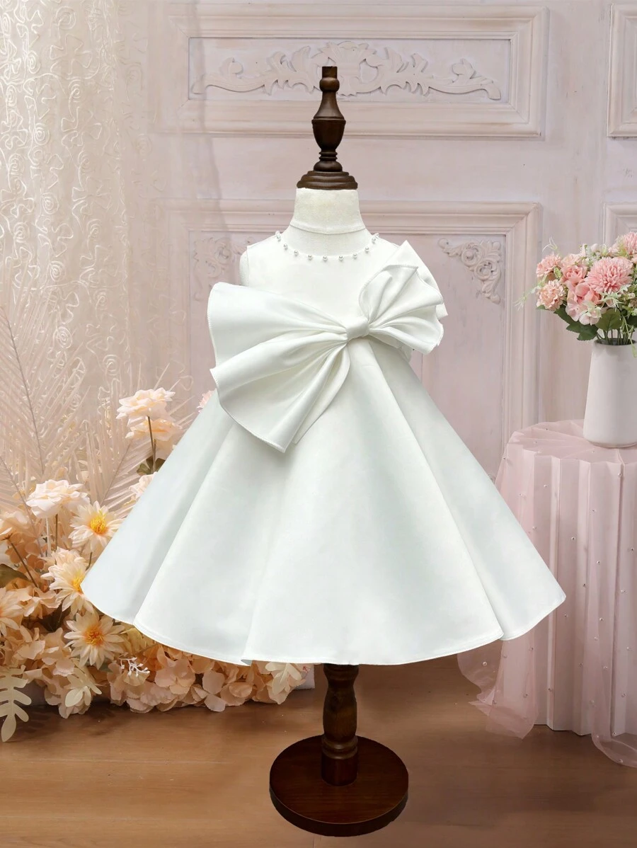 SHEIN Glamorique Kids Vestido de bebé sin mangas de color sólido y decoración de lazo esponjoso - Beis - Ver 1