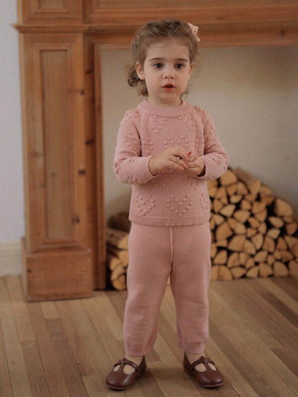 SHEIN Conjunto de 2 piezas de suéter y pantalones de punto para bebé niña en primavera, otoño e invierno, nueva llegada de moda. Este conjunto rosa presenta un diseño único con un patrón de corazón que le da un toque dulce.