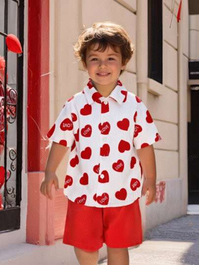 SHEIN Explorewe 小男孩心形印花短袖衬衫和红色短裤两件套。心形印花增添一丝俏皮，适合活泼好动的小男孩，也适合聚会穿着。红色短裤活力四射，充满童趣，与衬衫上的心形图案形成鲜明对比，情人节款。