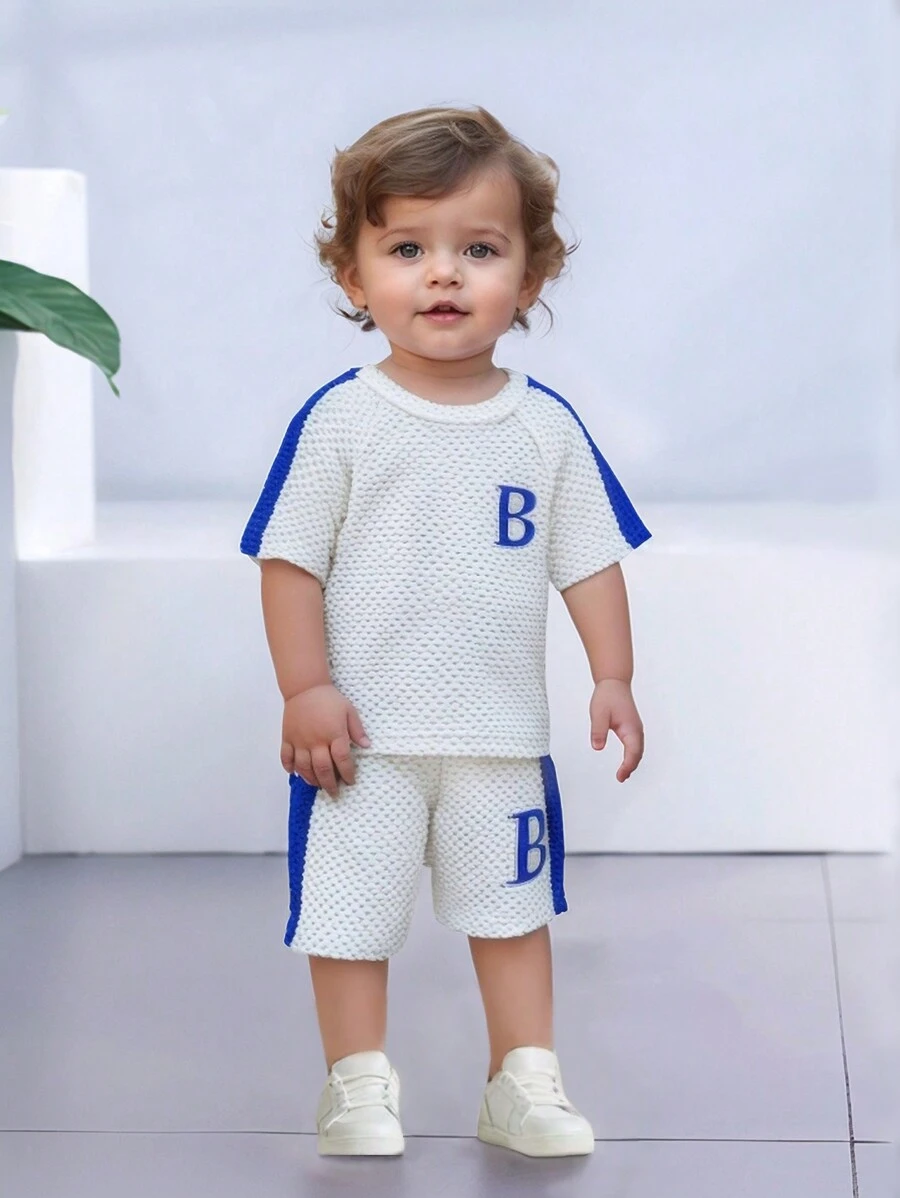 SHEIN 2 pièces Ensemble bébé garçon, nouveau t-shirt à manches courtes et short en tricot d'été à rayures à bulles minimaliste avec broderie lettres et couleurs contrastées, col rond, manches raglan. Combinaison de couleurs décontracté, broderie de lettre unique, tout-aller polyvalent, convient pour l'été, motif délicat, assortiment d'été, vêtements de sport, vacances, vêtements de jeu, tenue scolaire, tout-petit, unisexe, été - Blanc - Voir 1