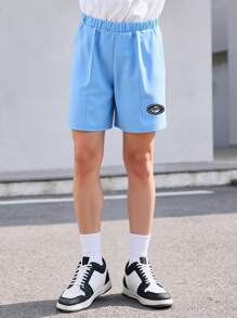 SHEIN 1 Pc Boys Casual Plain Loose Shorts, Featuring Minimalist Design With Patch At Hem. These Lightweight Blue Shorts Are Perfect For Summer Leisurewear, Suitable For Various Skin Tones And Occasions. The Simple Yet Elegant Design Prioritizes Comfort.