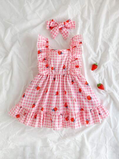 SHEIN Vintaside Kids 女宝宝吊带裙，粉白格纹设计，搭配可爱草莓印花，清新自然。裙摆肩部饰有荷叶边，完美诠释夏日时尚优雅活泼可爱气息。A字版型，采用轻薄透气面料，适合节日聚会、周岁婚礼、景区、拍照等场合穿着