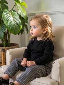 SHEIN Pantalones rectos de unicolor para niñas con diseño de costillas minimalista, que muestran el profesionalismo y la moda del bebé. Hechos de tela premium, la silueta recta clásica se combina con patrones mínimos, creando un estilo atemporal. Estos pantalones son adecuados para varios escenarios de uso: ya sea aventuras al aire libre, disfrutar de la belleza del otoño, usar cómodamente en casa, tiempo de deportes activos y animados, u organizar relajadamente fiestas de vacaciones, pueden mantener al bebé elegante y cómodo, mostrando completamente su gusto de moda. - Gris - Ver 1