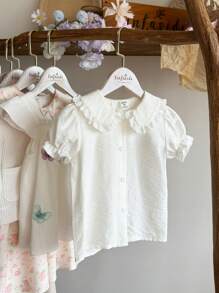 Vintaside Kids 这款少女假日圣诞休闲夏季纯白彼得潘领蕾丝短袖衬衫，时尚复古优雅，采用梭织面料，厚度适中，宽松版型，彼得潘领设计搭配精致蕾丝，展现独特的东方韵味，小泡泡袖短袖增添俏皮可爱，适合玩耍、度假、居家休闲，或与朋友在公园度过夏日假期。 - 白色 - 查看 3