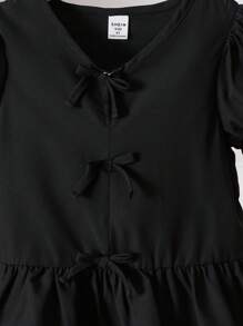 Blusa para niña con cuello en V, mangas abullonadas, volantes en el bajo y decoración de moño