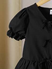 Blusa para niña con cuello en V, mangas abullonadas, volantes en el bajo y decoración de moño