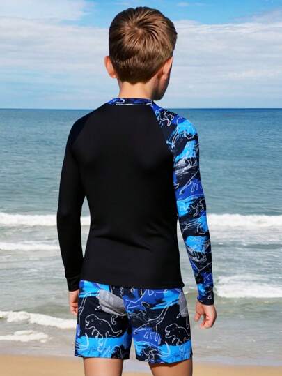 SHEIN 青少年男孩运动两件套泳衣，采用独特的恐龙印花设计。蓝色基调搭配活泼的印花，展现冒险精神。柔软舒适的材质，适合各种水上活动。长袖设计有效阻挡阳光并保护年轻皮肤。2025 年新款泳装系列，非常适合热爱游泳的青少年男孩，增强他们在水中的自信心。