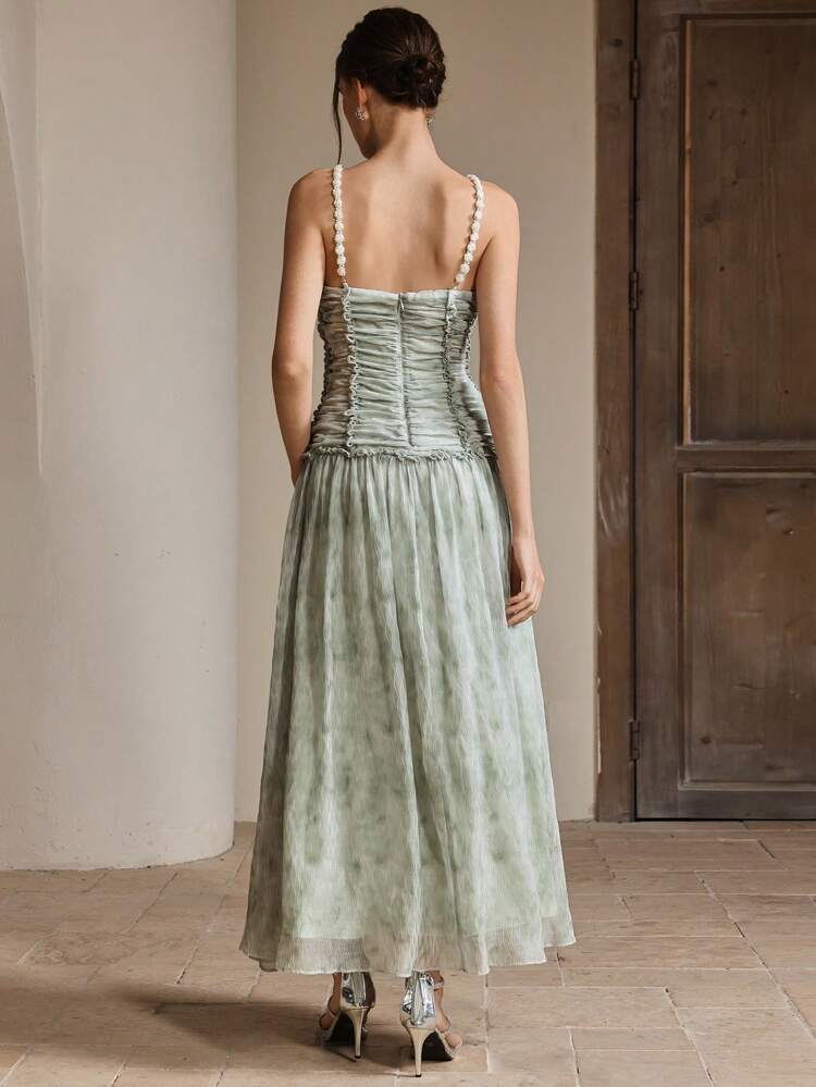Robe de soirée élégante et romantique avec dos nu, bretelles de perles, décolleté en V, volants à l'ourlet, texture. Tenues printanières et estivales pour femmes