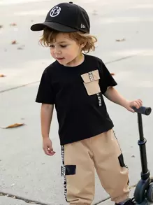 SHEIN 2 piezas Conjunto informal deportivo para niño pequeño - Camiseta negra de cuello redondo de manga corta con bolsillo de color contrastante y cinta con texto, combinada con pantalones cargo de cintura elástica, adecuado para juegos diarios al aire libre, escuela, deportes, viajes, primavera y verano