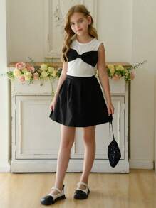 Klassieke witte T-shirt vest top met strik decor + zwarte patchwork geplooide mini rok set, zwart en wit kleurenschema toont elegante academische stijl. Delicate zwarte strik op de borst voegt een zoete sfeer toe, A-lijn rokontwerp flatteert het figuur. Geschikt voor lente/zomer alledaagse, campusactiviteiten, dates, casual uitjes, straalt jeugdige vitaliteit en verfijnde smaak uit