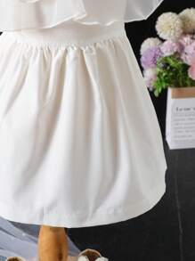 这款女婴优雅可爱简约的白色轻盈飘逸多层荷叶边网纱拼接针织连衣裙，采用不对称肩带设计，打造公主般的舞会蓬蓬裙造型，适合1-3岁宝宝。精准的腰部塑形和白色针织裙摆，整体甜美优雅又不失时尚感，公主般的设计，是生日派对、婚礼、宴会和其他正式场合的理想之选。春夏新款女婴连衣裙，白色女婴派对连衣裙。