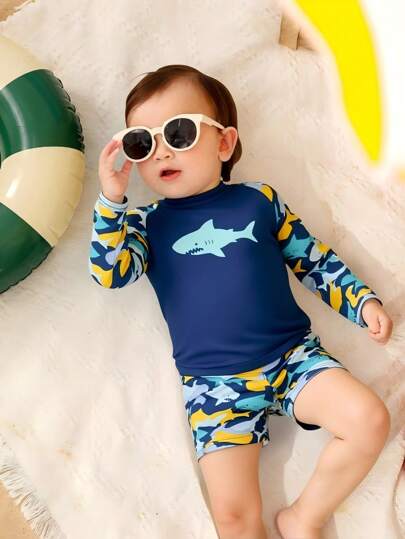 SHEIN مجموعة ملابس سباحة للأولاد الرضع، طقم تي شيرت طويل الأكمام مطبوع عليه سمكة قرش كرتونية ملونة وشورت سباحة، بمجموعة بوس