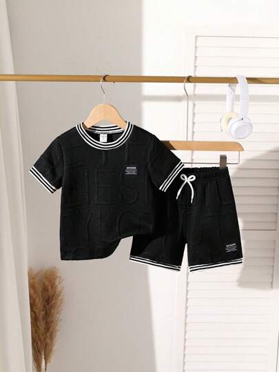 SHEIN 2 件装年轻男孩可爱简约休闲宽松运动学院套装，纯色纹理罗纹面料短袖圆领 T 恤，衣领、袖口和下摆处有黑白罗纹饰边，胸部刺绣黑色字母徽标，裤子配有黑色抽绳腰带和蝴蝶结，适合日常穿着、上学、户外玩耍、购物、餐饮、夏令营等，夏季