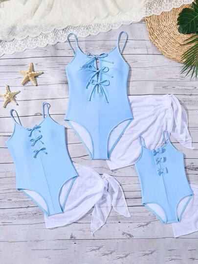 青春期前女孩纯蓝色连体泳衣，带蝴蝶结装饰和白色网眼裙