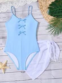 青春期前女孩纯蓝色连体泳衣，带蝴蝶结装饰和白色网眼裙