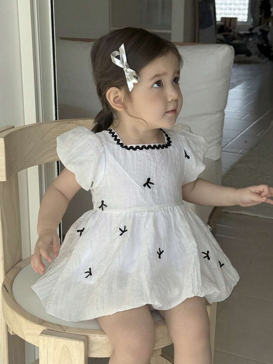 فستان فتيات صغيرات مطبوع برسوم الفراشات بأكمام منتفخة مطبوع بالكامل، مناسب للبنات الصغار للارتداء في جميع المناسبات الصيفية ، نسيج أبيض مع نمط أسود وحاشية دانتيل تجعل الطفلة تبدو أكثر فخامة وجذابة وعذبة - لون مشمشي - مشاهدة 1