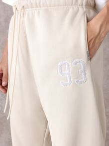 SUMWON Pantalón de chándal premium con pretina caída, números de equipo y detalles, cómodo ajuste para hacer ejercicio y uso casual en todas las estaciones