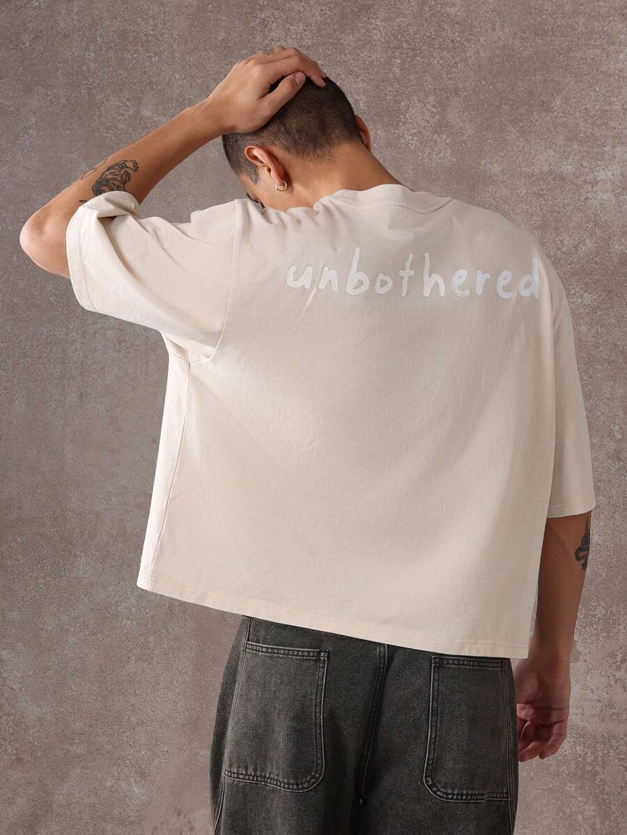 SUMWON Oversized unisex Statement Lifestyle kurzes T-Shirt, lässiger Street-Style, moderne urbane Mode, "Unbothered" Slogan Muster, Baumwoll-Jersey Loungewear Oberteil - Aprikosenfarben - Übersicht 1