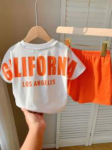 SHEIN Set de 2 piezas de ropa informal deportiva para niño/niña, estilo urbano con estampado de letras, que incluye una camiseta holgada de punto de cuello redondo y unos pantalones cortos de cintura elástica, apta para usar en primavera/verano tanto en casa como al aire libre