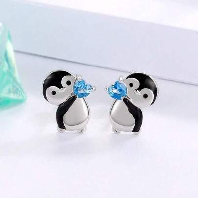 可愛的企鵝拿著藍色心形耳釘,送給女人和女孩的生日和聖誕節禮物
