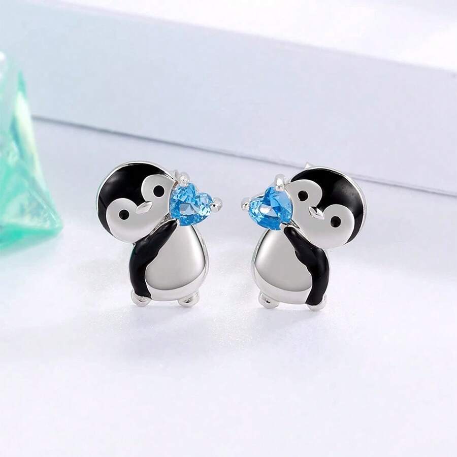 可愛的企鵝拿著藍色心形耳釘,送給女人和女孩的生日和聖誕節禮物
