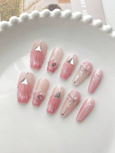 10片装手工按压式假指甲，长杏仁形裸粉色渐变，3D贝壳纹理，银色三角形装饰，珍珠点缀，银色链条镶嵌和虹彩水钻。裸粉色、粉色闪粉、银色调，四季皆宜，适合日常佩戴、约会、下午茶等优雅场合。尤其适合温柔少女、成熟女性和学生。套装包含一片果冻胶和一把指甲锉。
