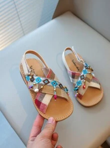 Nouvelles sandales pour enfants en bas doux de style national à la mode avec pendentif croix et pompon, que peuvent porter des amis ou des membres de la famille pour les vacances, les loisirs ou des activités en plein air.