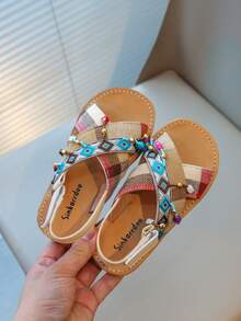 Nouvelles sandales pour enfants en bas doux de style national à la mode avec pendentif croix et pompon, que peuvent porter des amis ou des membres de la famille pour les vacances, les loisirs ou des activités en plein air.