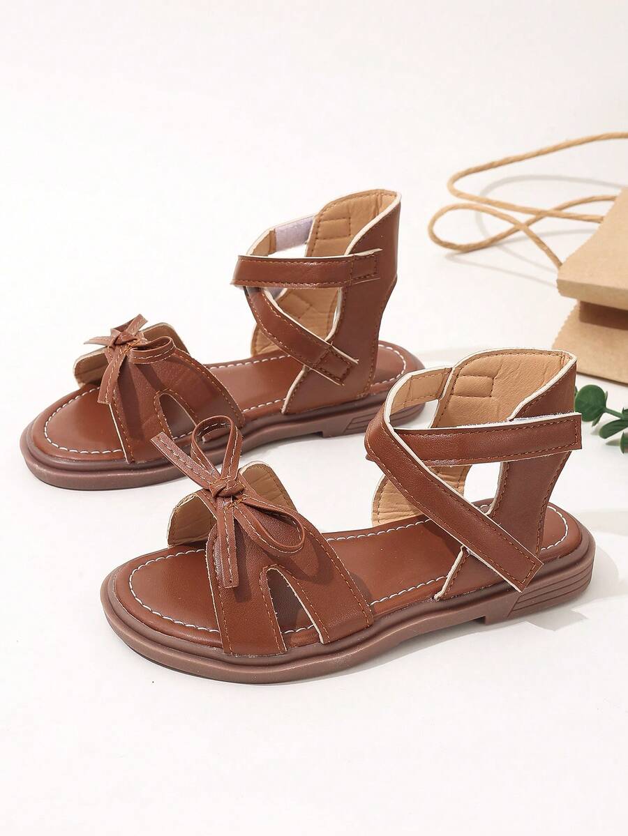 1 par de sandalias romanas planas para niñas con diseño de detalle de lazo hueco y banda de PU con lindo lazo para el verano