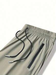 Pantalon de jogging casual d'été pour hommes, avec poches zippées, taille ajustable et détail réfléchissant. Confortable et extensible.