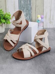 1對女童大尺寸羅馬涼鞋 - 米色，實色皮革和交叉帶掛鉤環，封閉式鞋頭和平底鞋，輕便、時尚、可愛，適合3-12歲女童夏季休閒、假日及沙灘派對穿著