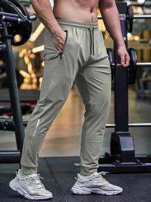 Pantalon de jogging casual d'été pour hommes, avec poches zippées, taille ajustable et détail réfléchissant. Confortable et extensible.