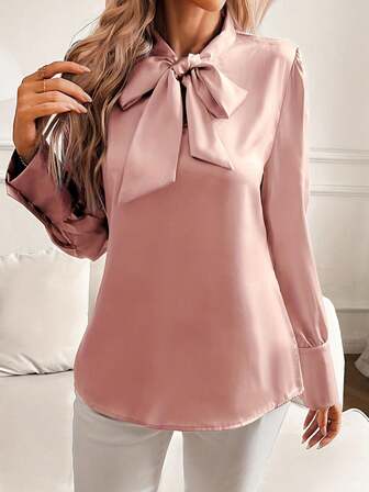 Blusa de satén rosa con cuello de lazo y mangas abullonadas - Elegante, blusa de seda adecuada para la oficina y ocasiones formales, que muestra un estilo de moda