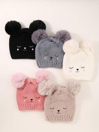 Ett babybarn Dubbelboll Stängda ögon leende ansikte Broderad stickad mössa