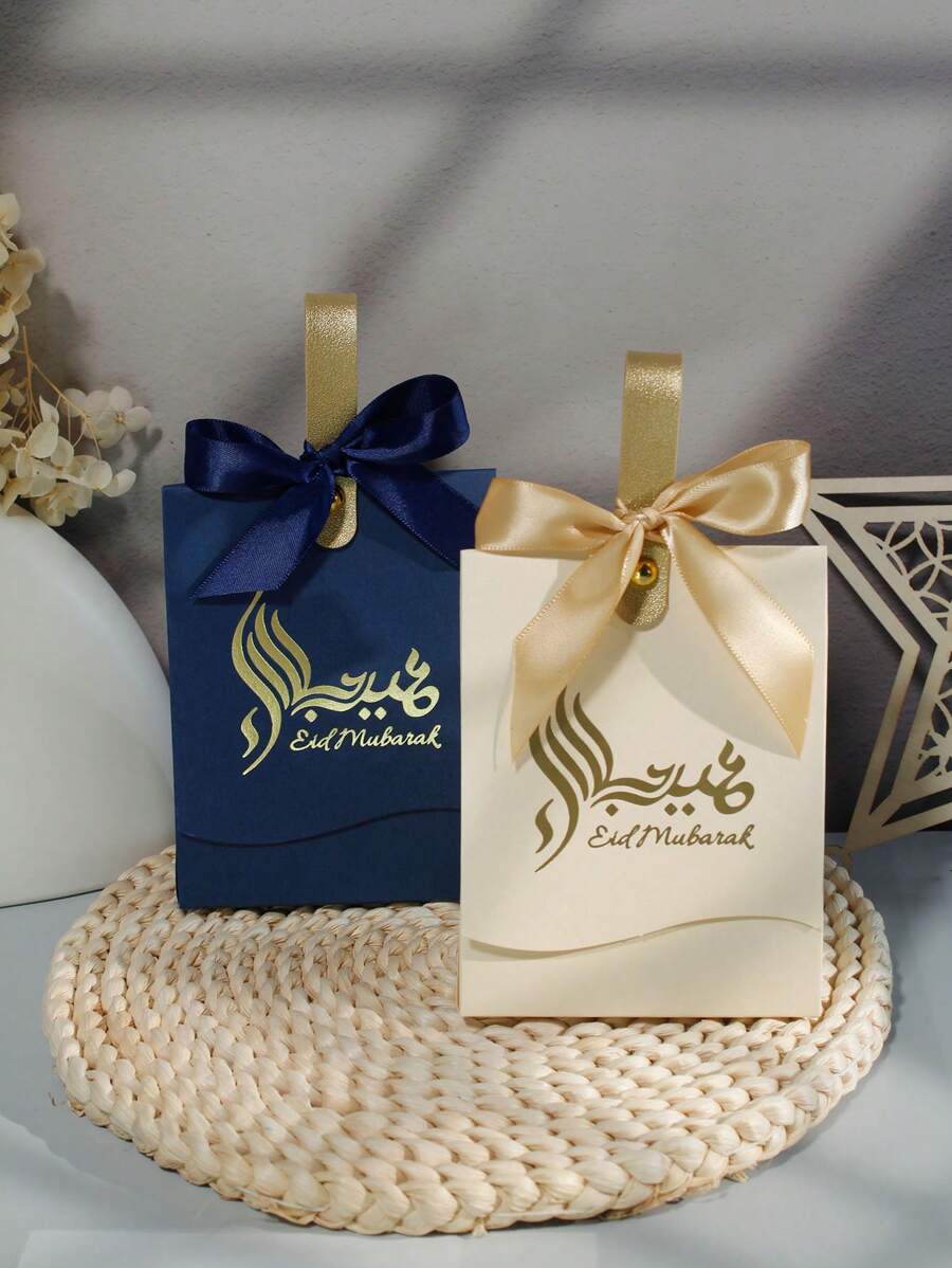 5 piezas de Bolsas de regalo mini de Eid Mubarak en azul marino y crema elegante con letra dorada y cintas de satín. Perfectos para dulces, chocolates y pequeños regalos. Ideal para celebraciones de Eid, ocasiones festivas y reuniones familiares. Embalaje elegante para momentos memorables - 10X6.5X12.5cm - Ver 1